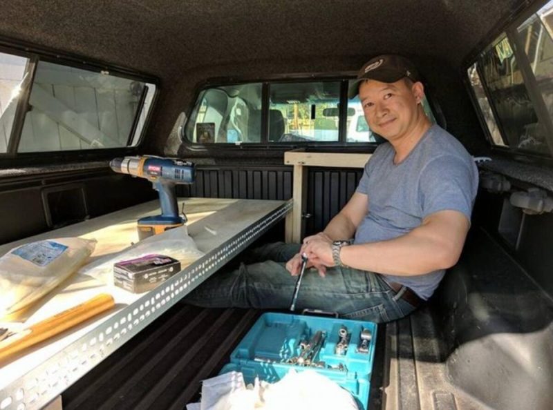 Lanon Baccam in the back of a truck sorting tools.