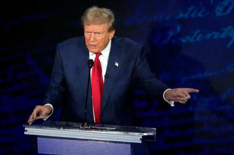Abortion Donald Trump in his trademark blue suit and red tie, standing at a podium at the debate, pointing at Kamala Harris. He's in the middle of saying something.