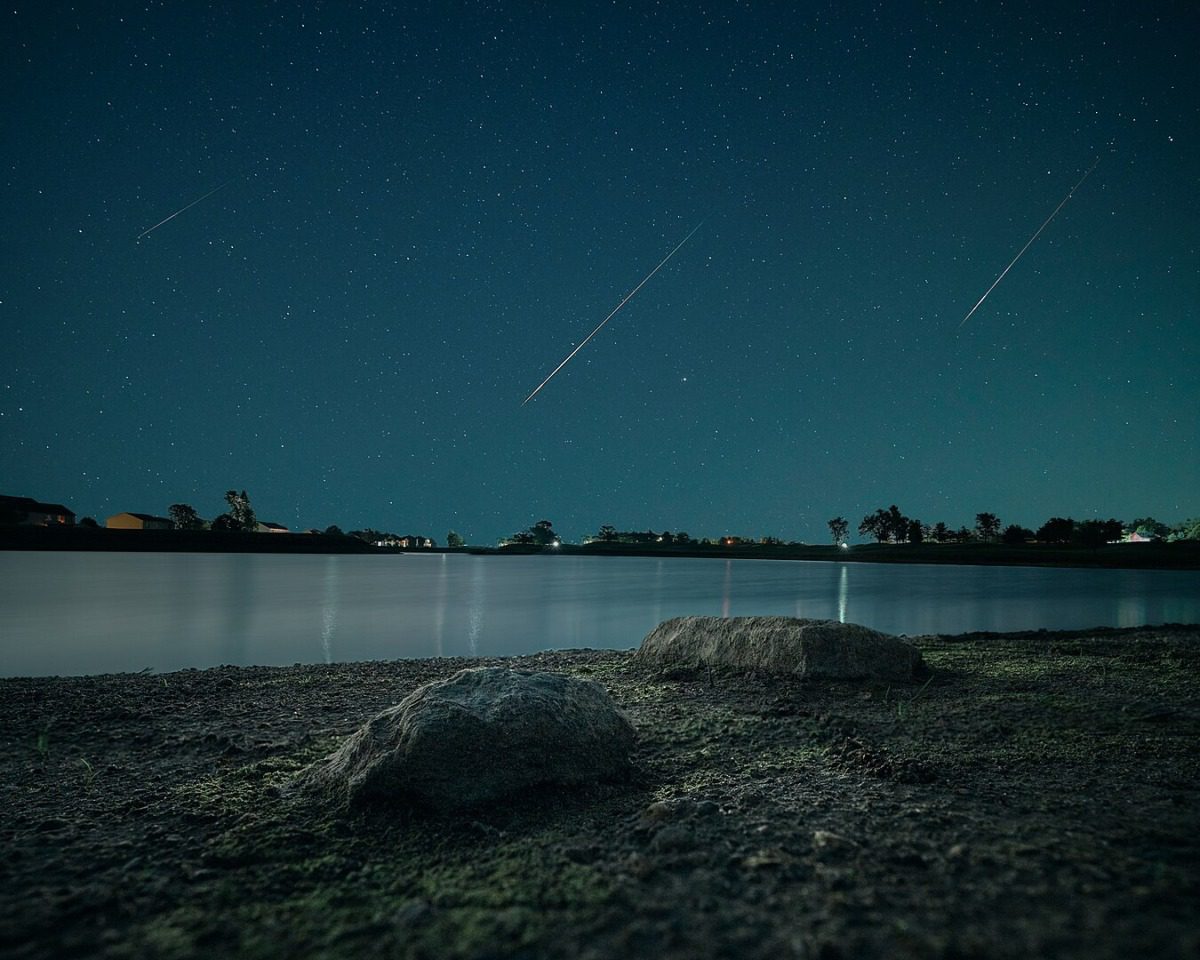 Meteor shower over a lake at night.