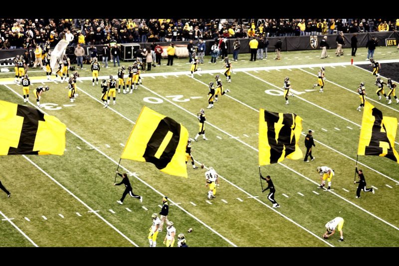 Football team holding Iowa flags on the field.