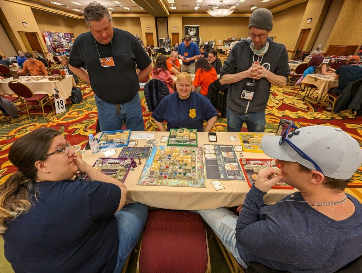 A group of people at a table covered with board games at Gamicon.