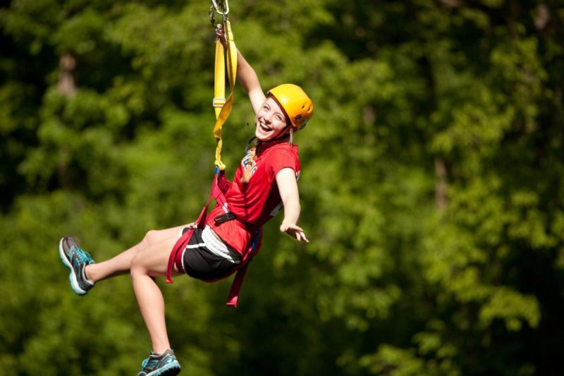 smiling woman riding an outdoor zipline